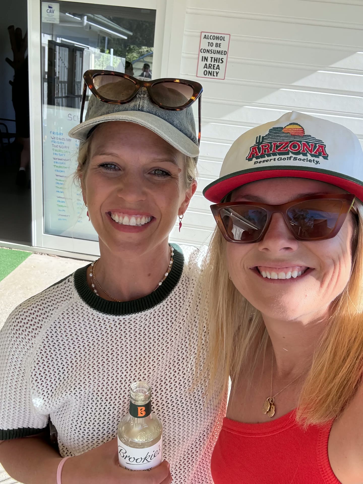 Two friends smiling with drinks at a mully club event
